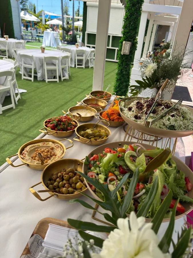 שולחן שוק באירוע גן עם חומוס, זיתים וסלטים טריים